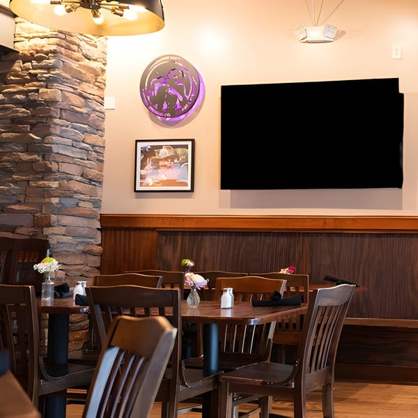 Interior of Mayworth's Public House with wooden tables and chairs, a stone pillar, and a large TV.